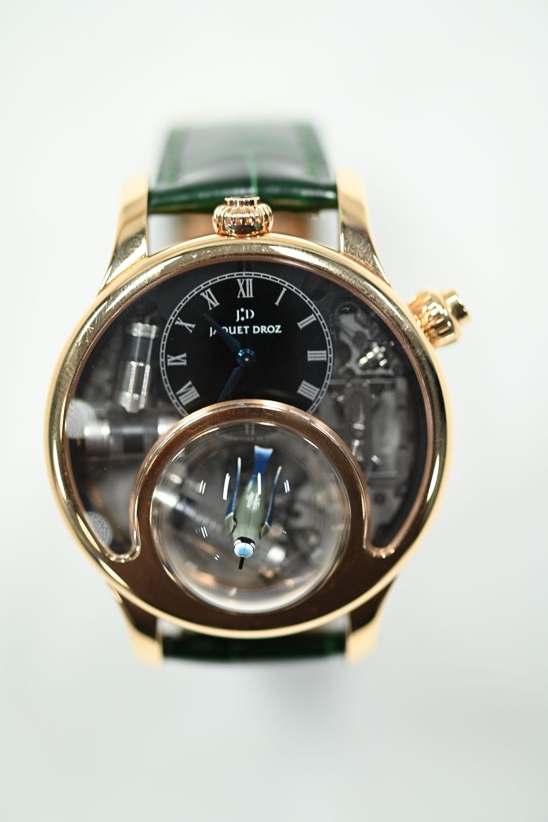 Jaquet Droz Charming Bird in red gold with black dial and a singing bird automaton beneath a sapphire dome, on a green alligator strap